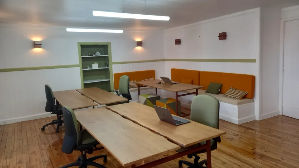 Fotografía de archivo: sala de trabajo compartido (coworking) con mesas de madera, sillas y portátiles.
